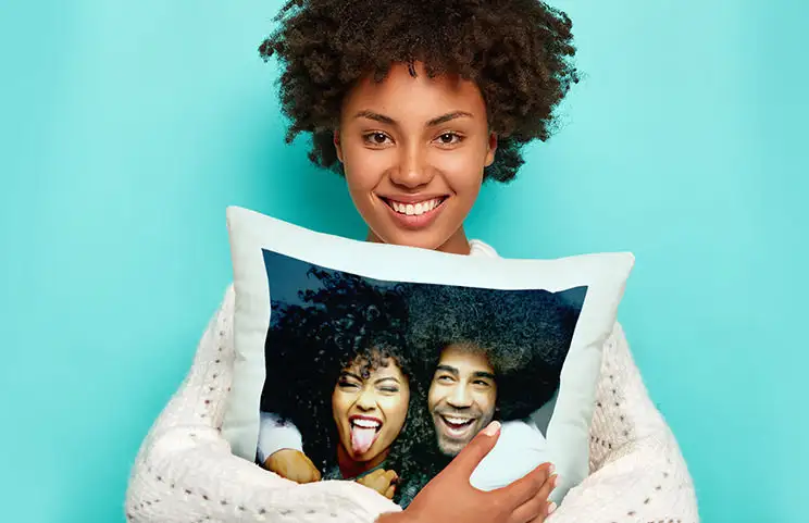Femme souriante câlinant un oreiller personnalisé avec photo de couple, cadeau unique et original.